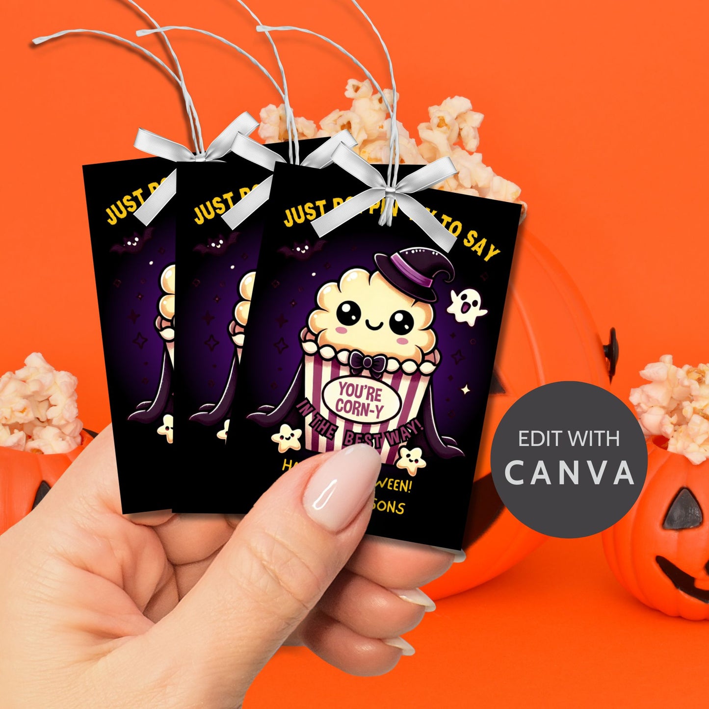 Halloween-themed printable gift tags with the message "Just Poppin' By to Say You're Corn-y in the Best Way" featuring a cute popcorn character dressed in Halloween attire. Tags are 2.5 x 3.5 inches, laid out 8 per sheet on a standard 8.5 x 11-inch page. Includes a printable PDF and a PDF with a link to an editable Canva template.
