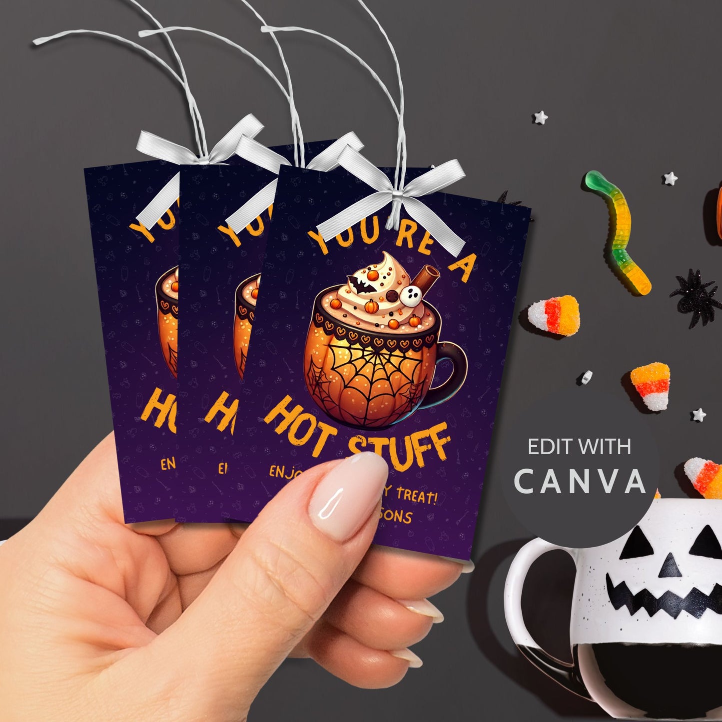 Halloween-themed printable gift tags with the message "You're a Hot Stuff" featuring a festive mug of hot cocoa on a dark purple background. Tags are 2.5 x 3.5 inches, laid out 8 per sheet on a standard 8.5 x 11-inch page. Includes a printable PDF and a PDF with a link to an editable Canva template.