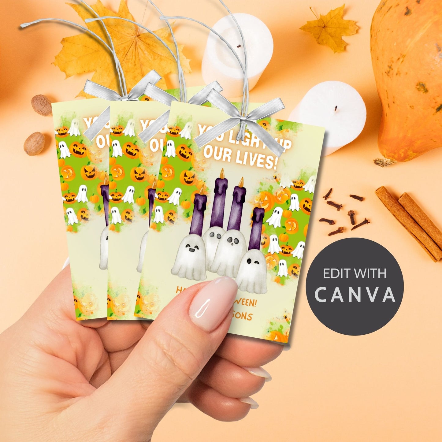 Halloween-themed printable gift tags with the message "You Light Up Our Lives!" designed for candle gifts, featuring cute ghost characters and glowing candles on a festive background. Tags are 2.5 x 3.5 inches, laid out 8 per sheet on a standard 8.5 x 11-inch page. Includes a printable PDF and a PDF with a link to an editable Canva template.
