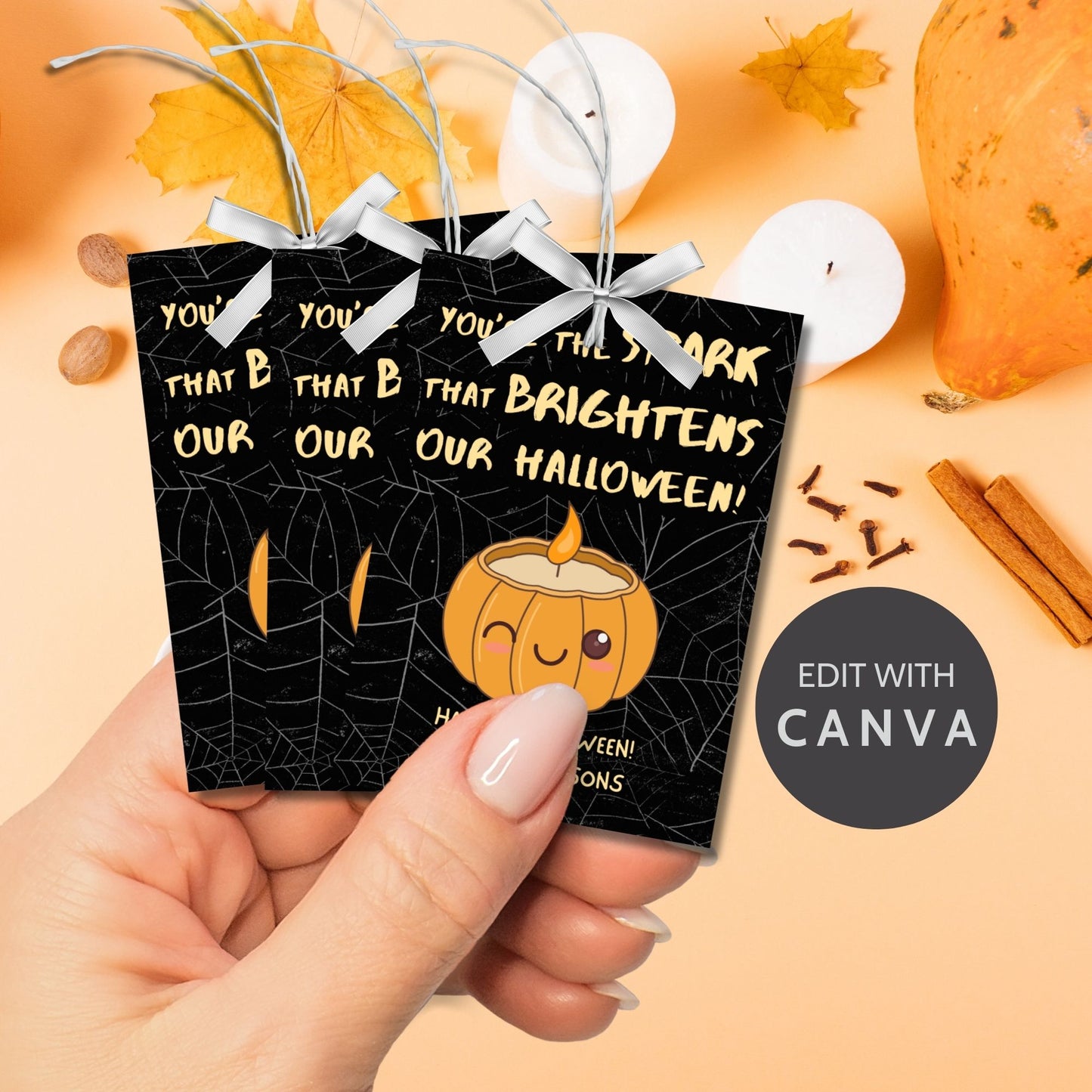 Halloween-themed printable gift tags with the message "You're the Spark that Brightens Our Halloween!" featuring a cute pumpkin candle on a black spiderweb background. Tags are 2.5 x 3.5 inches, laid out 8 per sheet on a standard 8.5 x 11-inch page. Includes a printable PDF and a PDF with a link to an editable Canva template.