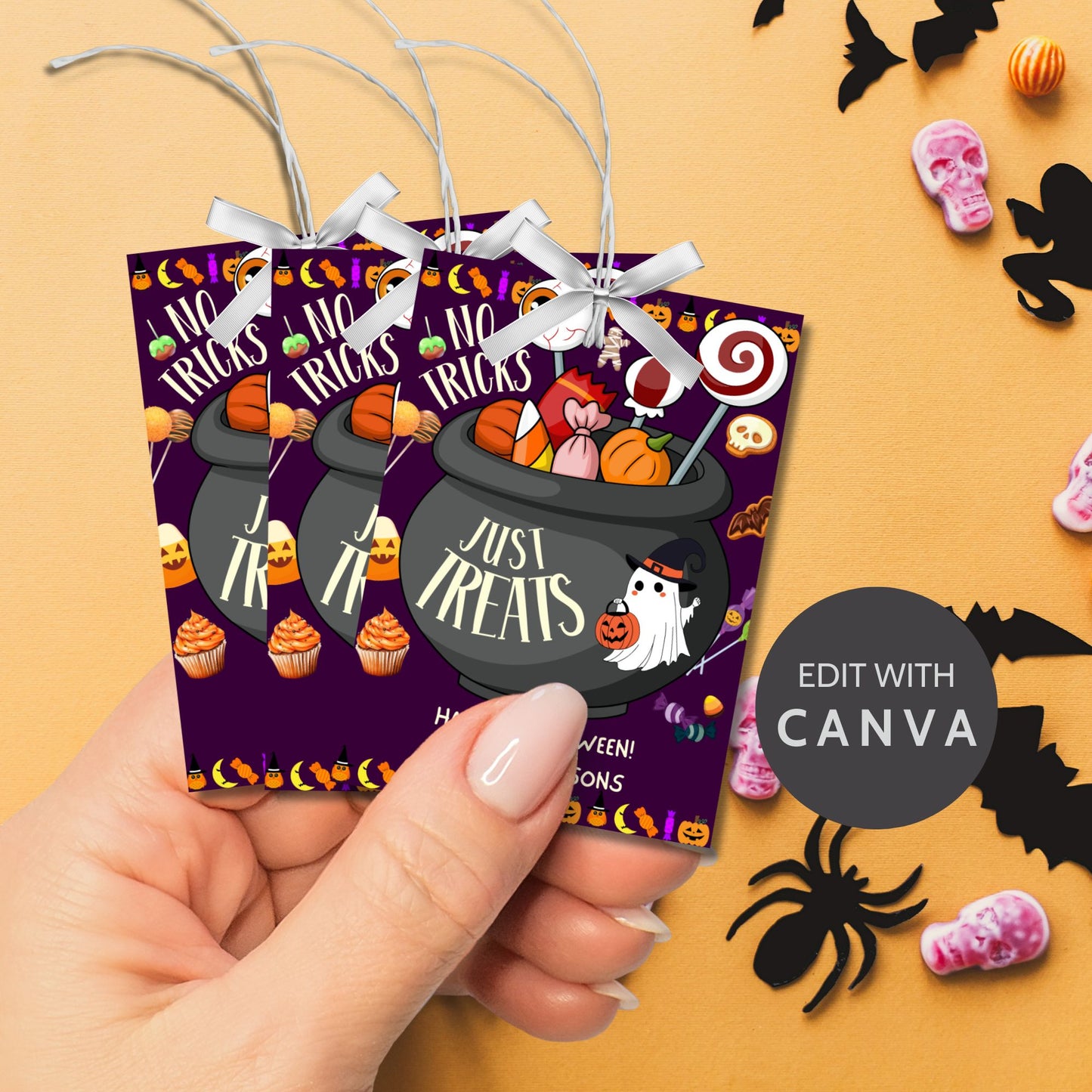 Halloween-themed printable gift tags with the message "No Tricks, Just Treats" featuring a cauldron filled with Halloween candies and treats. Tags are 2.5 x 3.5 inches, laid out 8 per sheet on a standard 8.5 x 11-inch page. Includes a printable PDF and a PDF with a link to an editable Canva template.
