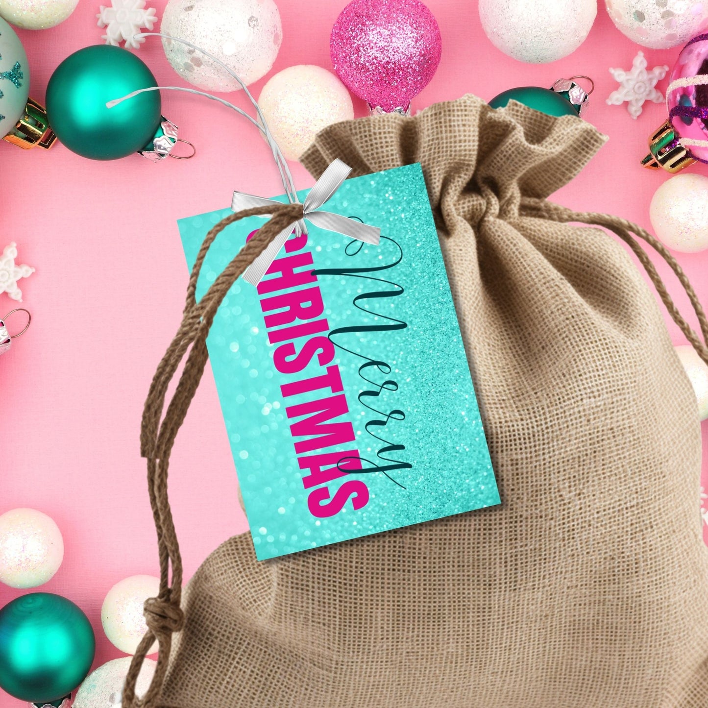 Printable Christmas gift tags featuring an aqua glitter background with bold magenta "Merry Christmas" text and black script accents, sized 2.5 x 3.5 inches, 8 tags per sheet.