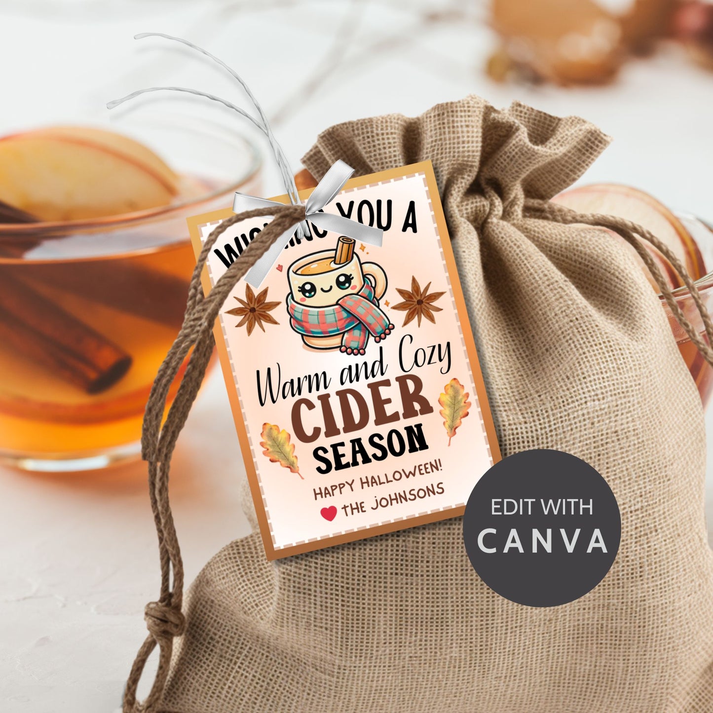 A printable Halloween gift tag featuring a warm and cozy cider theme. The tag displays a cute mug wrapped in a scarf, surrounded by autumn leaves and star anise, with the message "Wishing You a Warm and Cozy Cider Season."