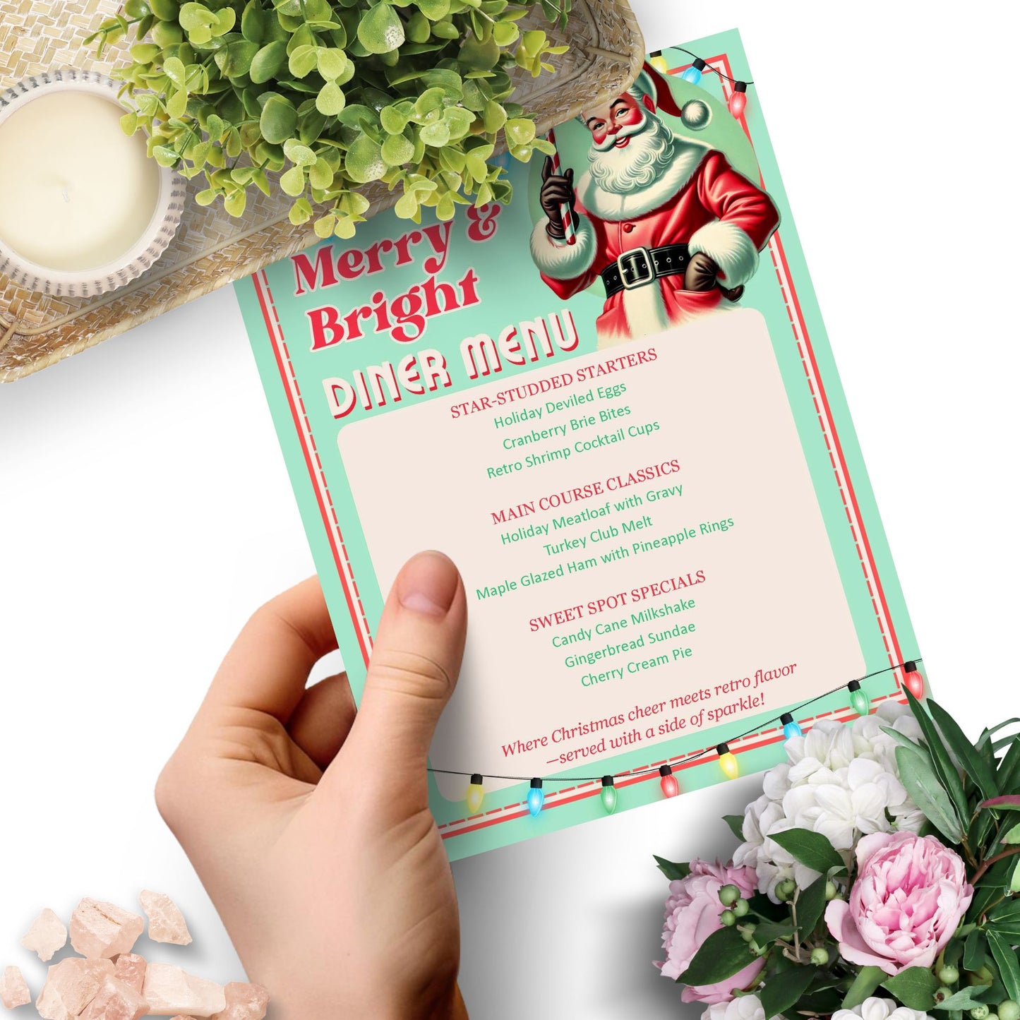 Hand holding a 'Merry & Bright Diner Menu' with Santa Claus illustration, surrounded by flowers and a candle.