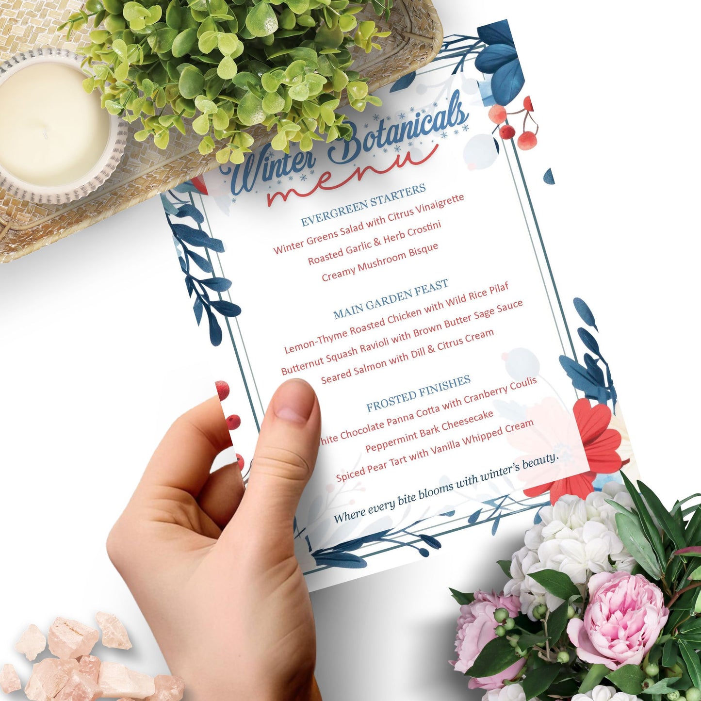 Hand holding a 'Winter Botanicals Menu' with floral decorations and a candle.