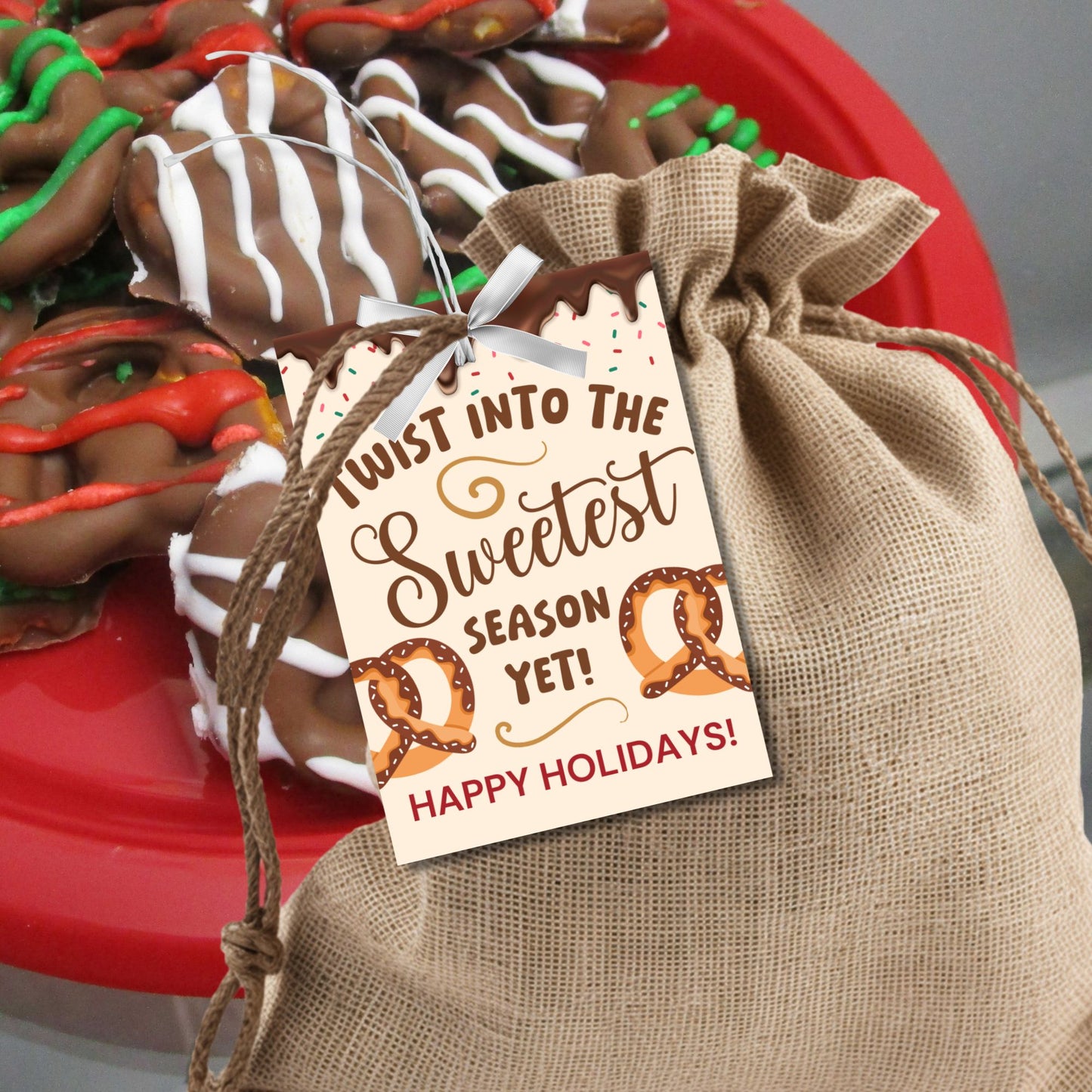 Printable holiday gift tags reading "Twist Into the Sweetest Season Yet!" with pretzel illustrations, chocolate drizzle, and sprinkles. Perfect for pretzel-themed gifts. Includes printable PDF and editable Canva template.