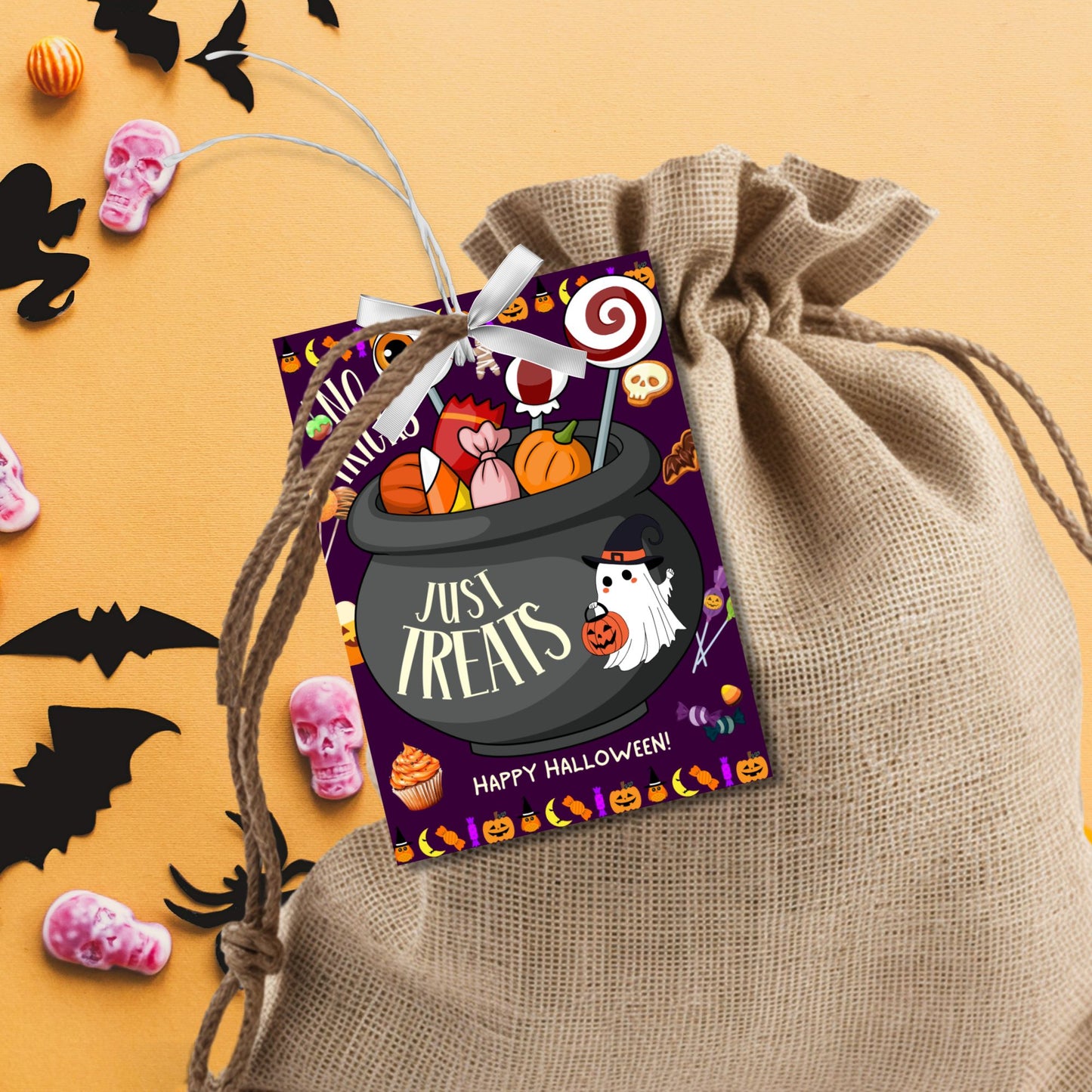 Halloween-themed printable gift tags with the message "No Tricks, Just Treats" featuring a cauldron filled with Halloween candies and treats. Tags are 2.5 x 3.5 inches, laid out 8 per sheet on a standard 8.5 x 11-inch page. Includes a printable PDF and a PDF with a link to an editable Canva template.