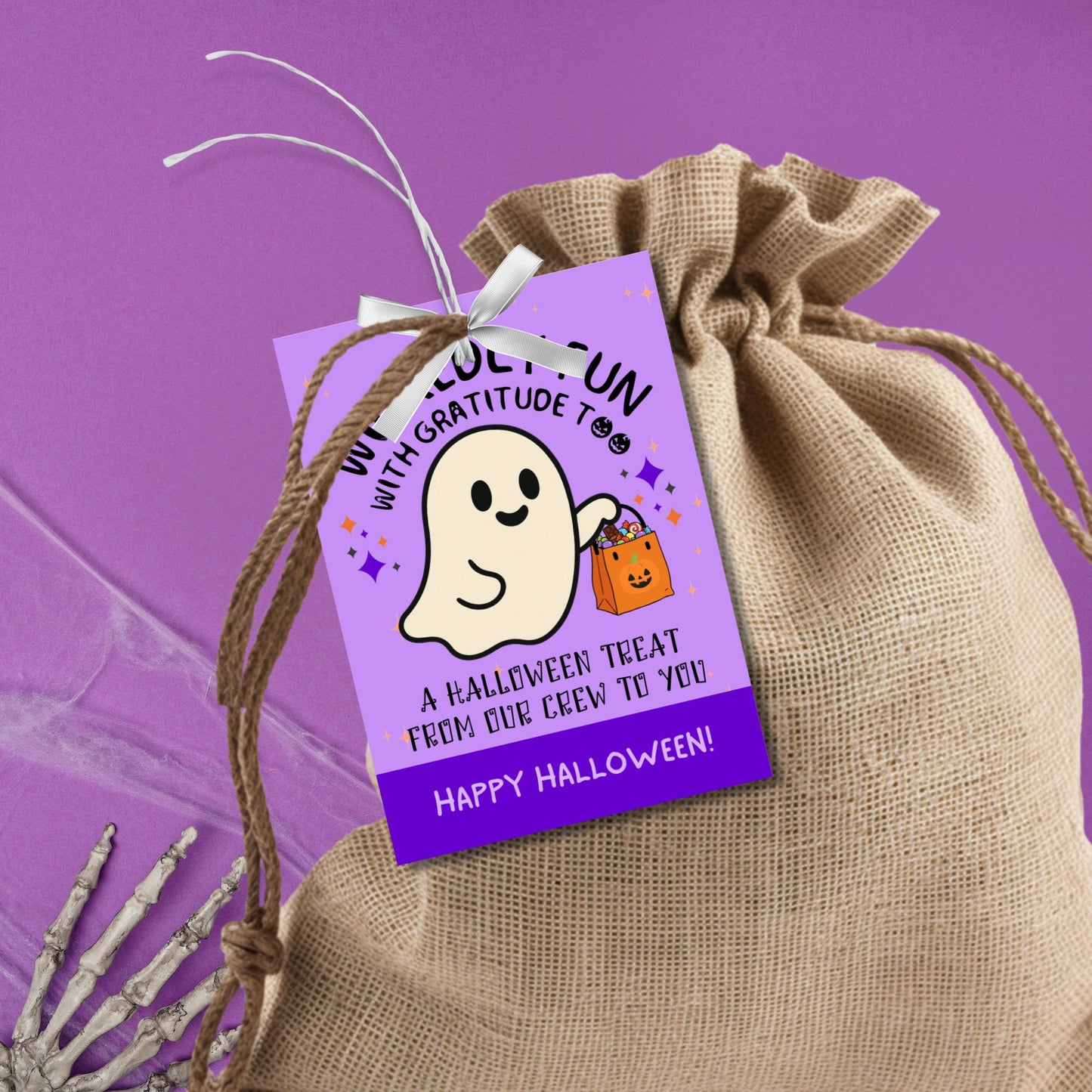Halloween-themed gift tag with a ghost design on a purple background, attached to a burlap bag against a purple background.