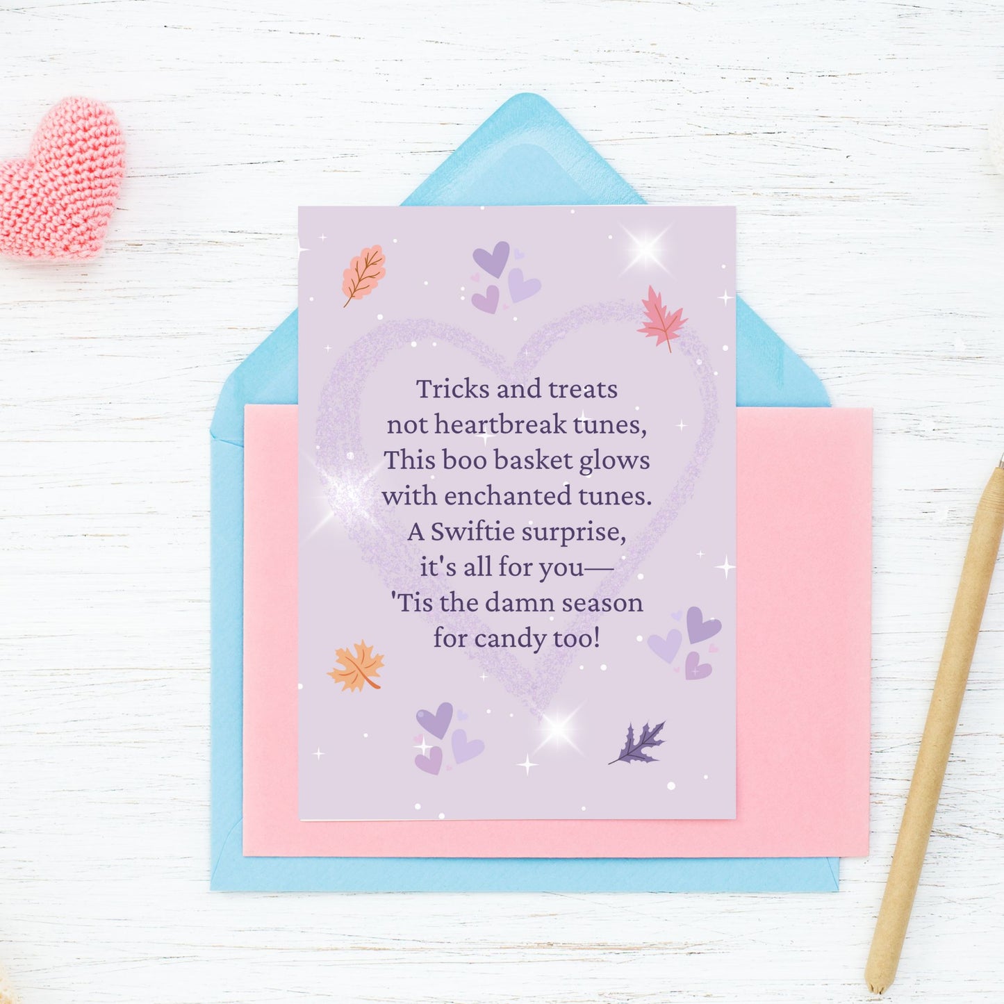 Greeting card with a purple background and decorative elements on a white wooden surface.