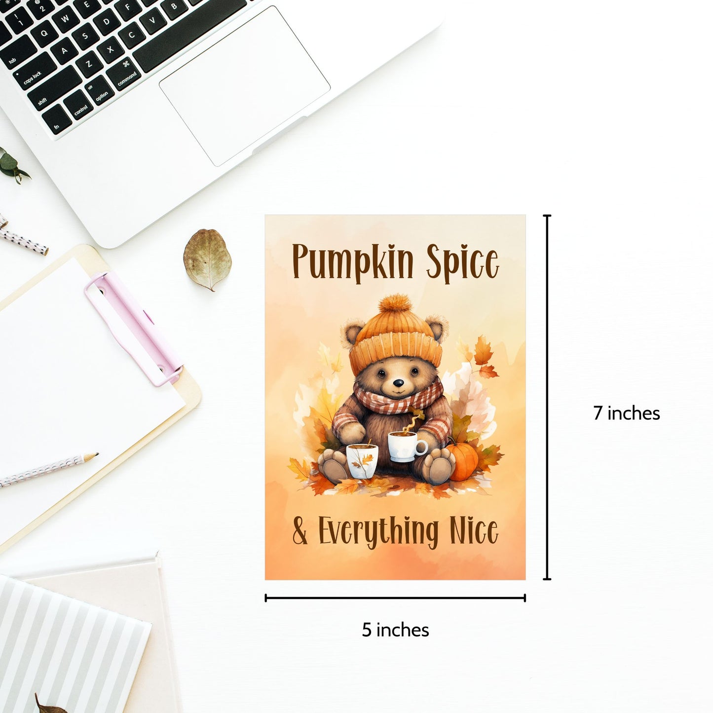 Poster with a bear holding a pumpkin spice latte, text 'Pumpkin Spice & Everything Nice', and dimensions on a desk.