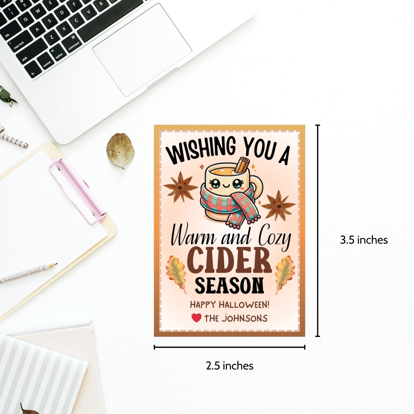 A printable Halloween gift tag featuring a warm and cozy cider theme. The tag displays a cute mug wrapped in a scarf, surrounded by autumn leaves and star anise, with the message "Wishing You a Warm and Cozy Cider Season."