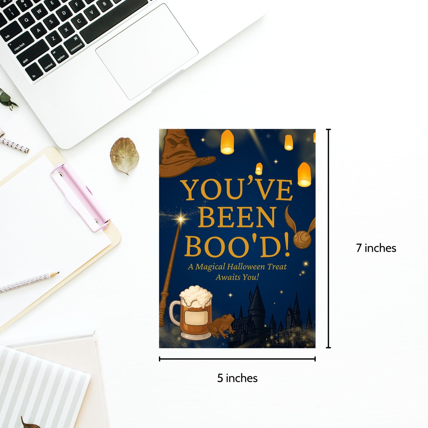 Halloween-themed card with text 'You've Been Boo'd!' on a desk with laptop and stationery items.