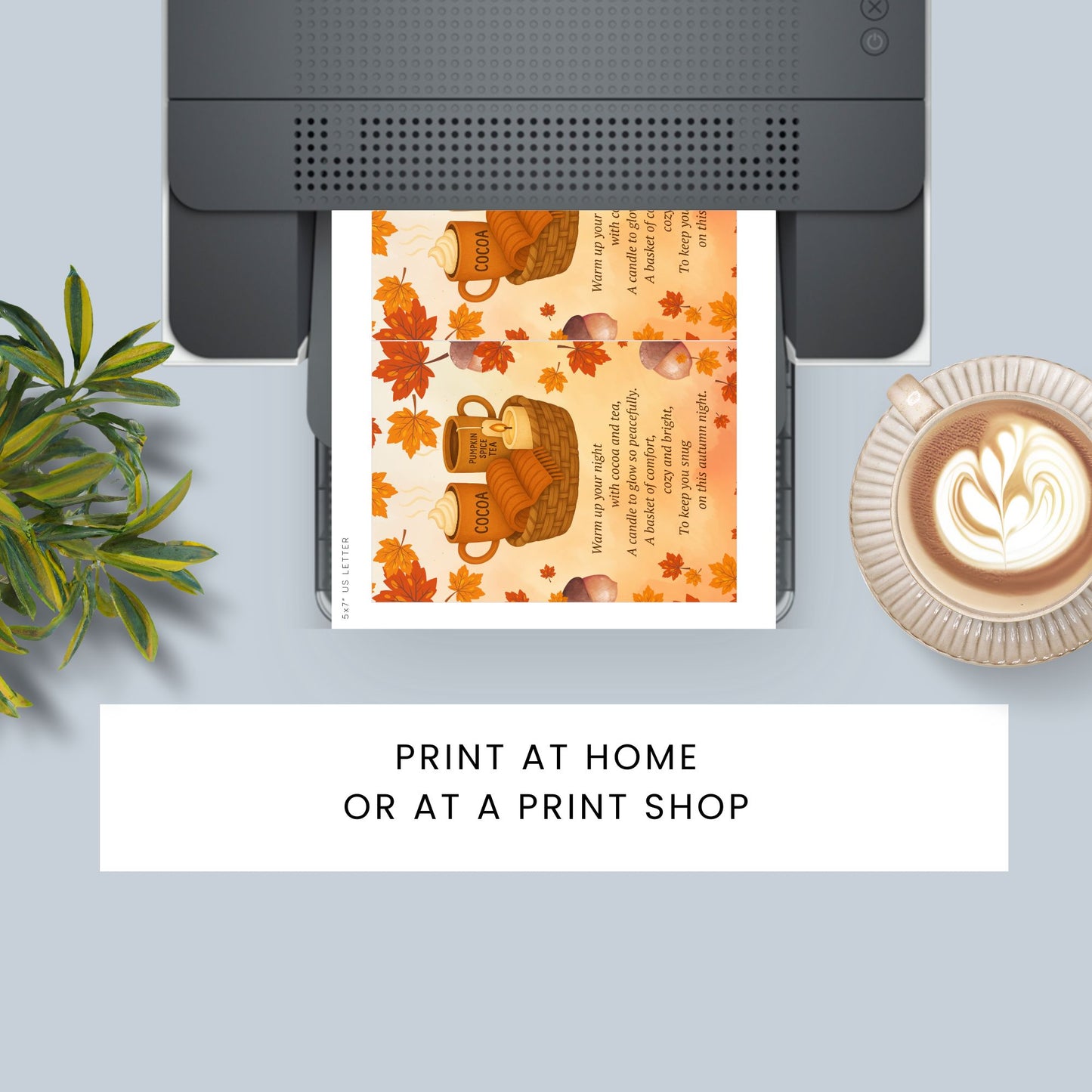 Printer with a printed card featuring autumn design on a light blue surface with a plant and coffee cup.
