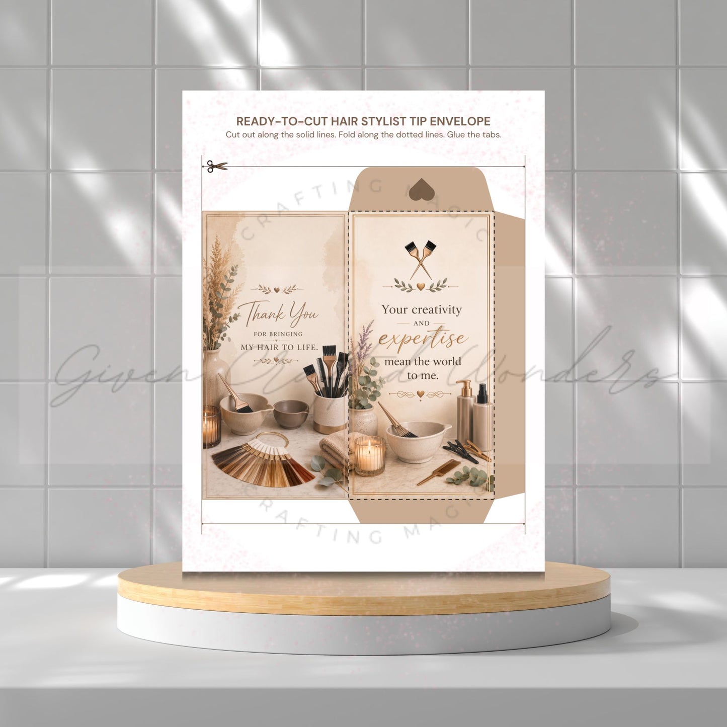 A ready-to-cut hair stylist tip envelope card set displayed on a light wood and white round pedestal against a gray tiled wall. The set includes a white envelope with printed text and a kraft paper envelope featuring a beige background, decorative hair tools, and styling accessories.