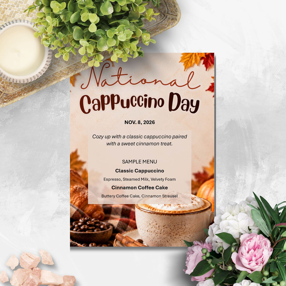 A National Cappuccino Day invitation card styled in a flat-lay arrangement with a hot cappuccino, coffee beans, autumn leaves, and flowers on a light gray marble background.