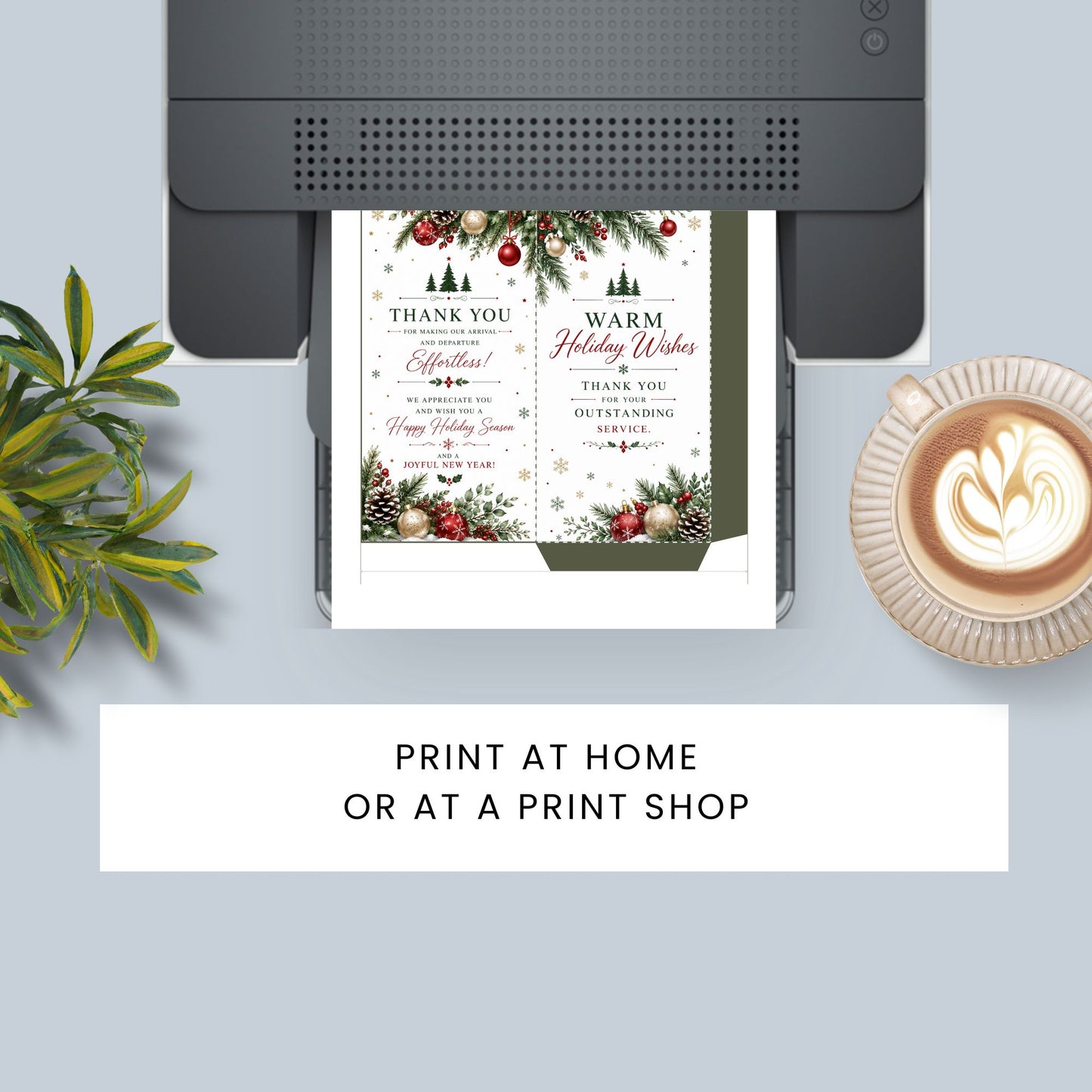 A holiday-themed printable invitation card shown being printed by a black printer, with a coffee cup and green leaves as props on a light gray background. Text at the bottom reads 'PRINT AT HOME OR AT A PRINT SHOP'.