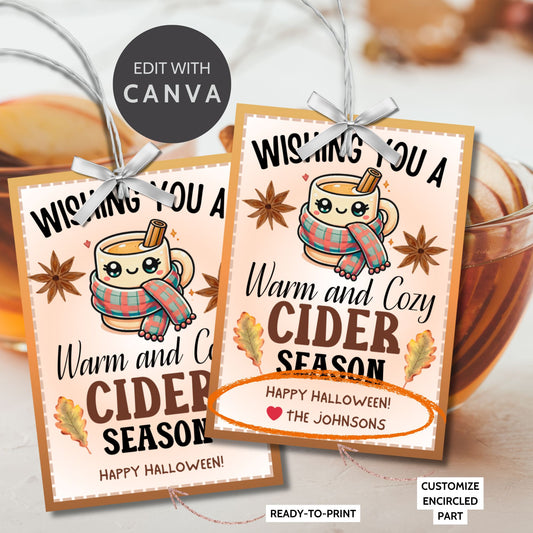 A printable Halloween gift tag featuring a warm and cozy cider theme. The tag displays a cute mug wrapped in a scarf, surrounded by autumn leaves and star anise, with the message "Wishing You a Warm and Cozy Cider Season."