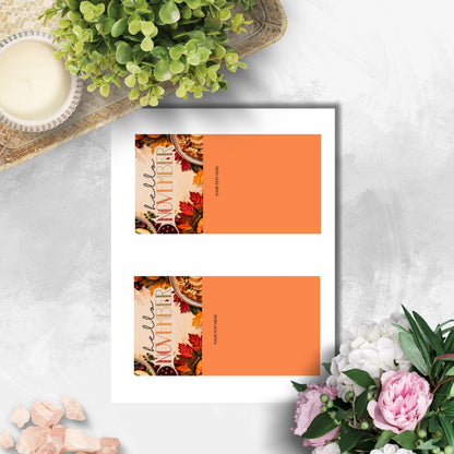 A printed card template sheet with two identical fall-themed 'Hello November' cards, shown on a light gray textured surface with decorative flowers, a candle, and greenery around it.