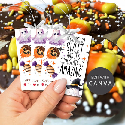 Halloween-themed printable gift tags with the message "You're So Sweet and It's Chocolate-ly Amazing" featuring cute ghosts, witches' hats, and chocolate candies. Tags are 2.5 x 3.5 inches, laid out 8 per sheet on a standard 8.5 x 11-inch page. Includes a printable PDF and a PDF with a link to an editable Canva template.