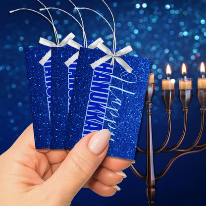 A set of printable Hanukkah gift tags featuring "Happy Hanukkah" in white and blue text on a sparkling blue glitter background. Perfect for Hanukkah gift wrapping.