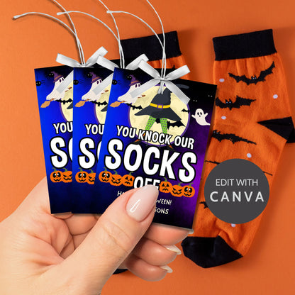 Halloween-themed printable gift tags with the message "You Knock Our Socks Off!" featuring a witch's hat, spooky ghosts, and jack-o'-lanterns, perfect for sock gifts. Tags are 2.5 x 3.5 inches, laid out 8 per sheet on a standard 8.5 x 11-inch page. Includes a printable PDF and a PDF with a link to an editable Canva template.