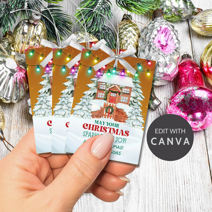 Christmas gift tags featuring a cozy snow-covered house decorated with festive lights, paired with the message "May Your Christmas Sparkle with Joy!" These printable and editable tags add a warm and festive touch to holiday gifts.