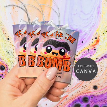 Halloween-themed printable gift tags with the message "You're the Bomb" featuring a cute and spooky bath bomb character, perfect for bath bomb gifts. Tags are 2.5 x 3.5 inches, laid out 8 per sheet on a standard 8.5 x 11-inch page. Includes a printable PDF and a PDF with a link to an editable Canva template.