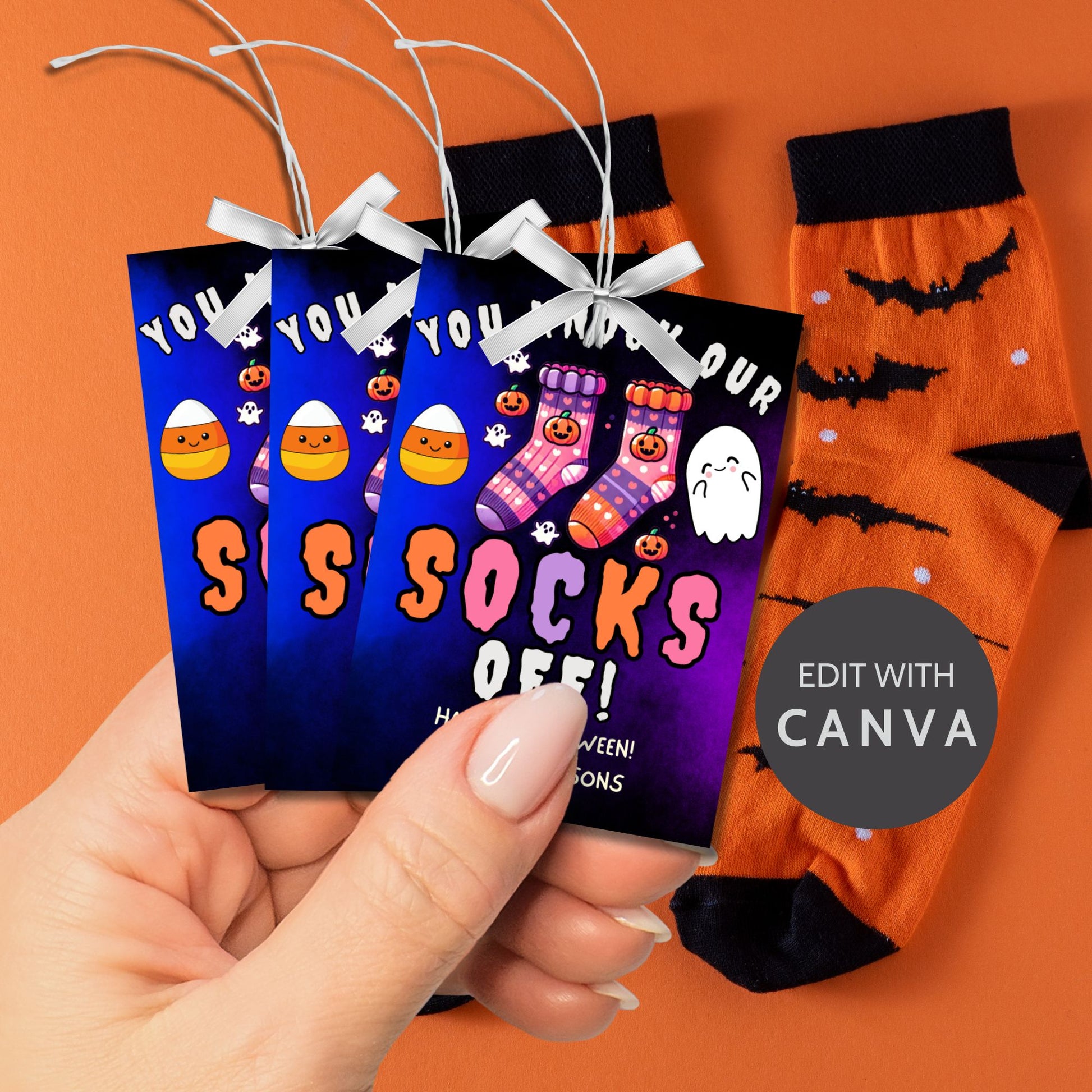 Halloween-themed printable gift tags with the message "You Knock Our Socks Off!" featuring colorful Halloween socks, ghosts, and candy corn. Tags are 2.5 x 3.5 inches, laid out 8 per sheet on a standard 8.5 x 11-inch page. Includes a printable PDF and a PDF with a link to an editable Canva template.