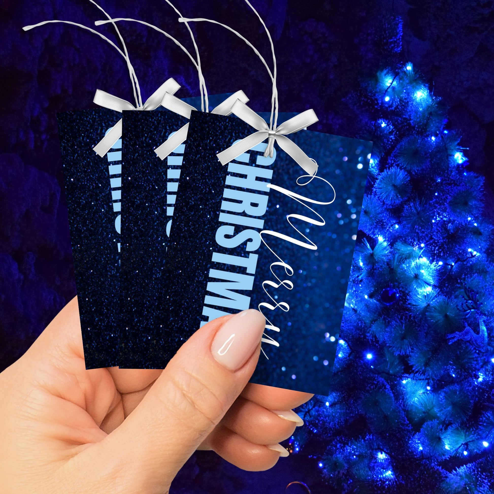 Printable blue Christmas gift tags with a glittery blue background and bold light blue "Merry Christmas" text, sized 2.5 x 3.5 inches, 8 tags per sheet.