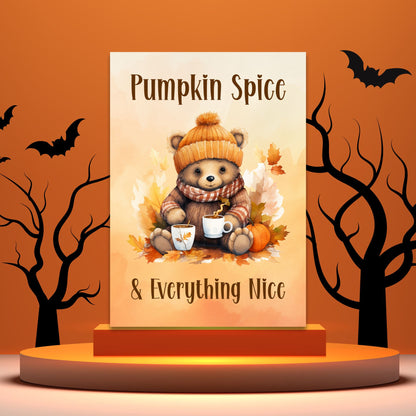 Decorative sign with a bear holding pumpkin spice-themed items against an orange background with bats and trees.