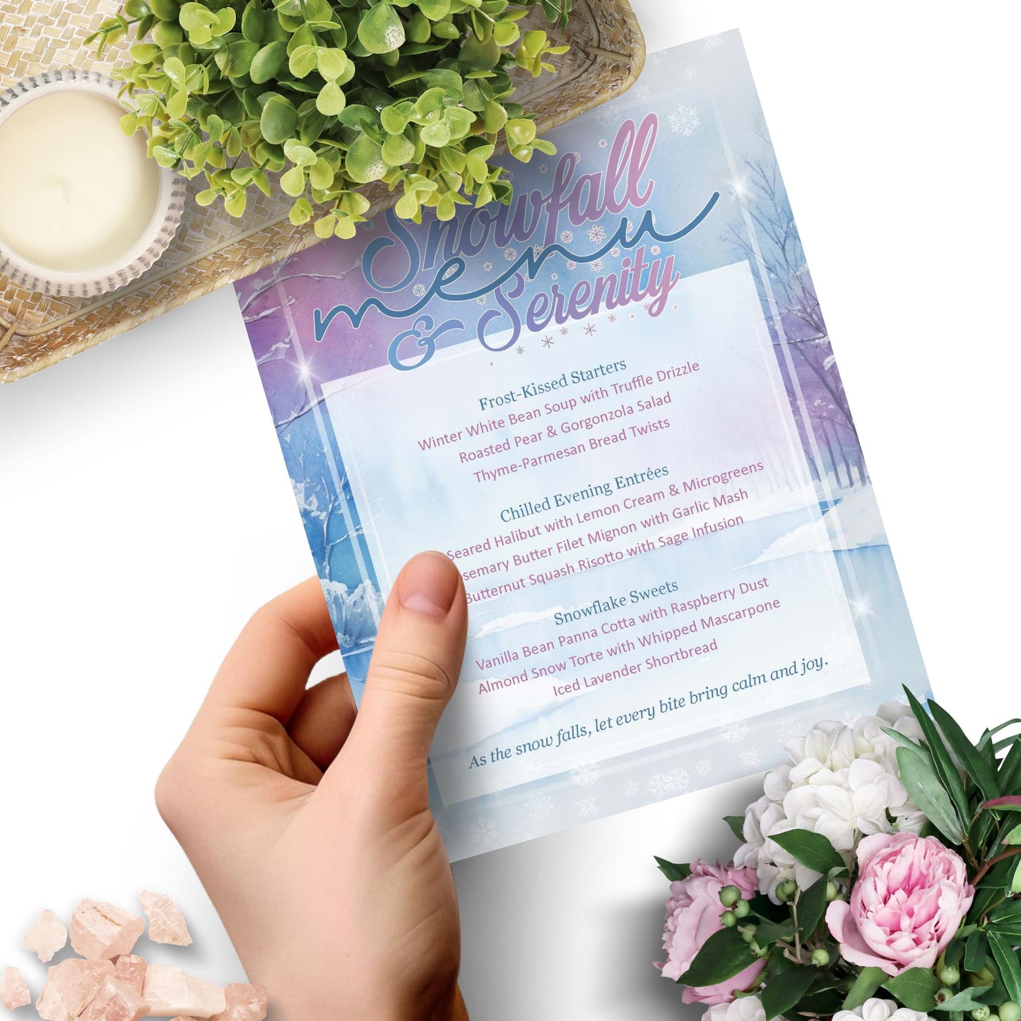 Hand holding a menu titled 'Snowfall & Serenity' with floral and decorative elements on a white background