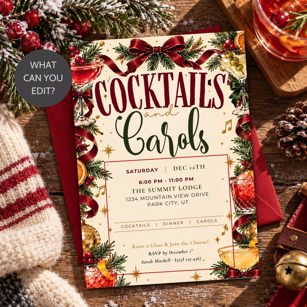 A festive Christmas-themed cocktail and carol event invitation card with red ribbons, green pine branches, ornaments, and holiday illustrations, placed on a wooden surface with a red envelope, a striped knit blanket, pinecones, and a glass of holiday drink. A dark gray circular badge in the upper left reads 'WHAT CAN YOU EDIT?'.