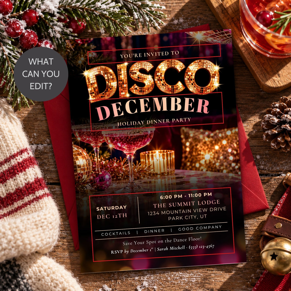A festive disco December holiday dinner party invitation card layered over a red envelope, styled on a rustic wooden table with a knit sweater, pinecones, evergreen branches, and a glass of red drink.