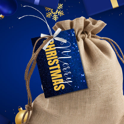 Printable blue and gold Christmas gift tags featuring a sparkling blue glitter background and bold gold "Merry Christmas" text, sized 2.5 x 3.5 inches, 8 per sheet.