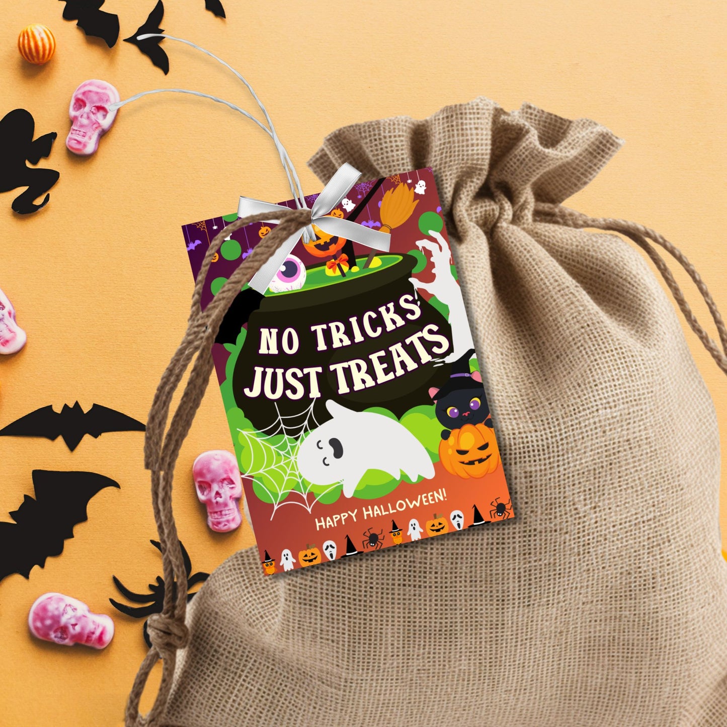 Halloween-themed printable gift tags with the message "No Tricks, Just Treats" featuring colorful cauldrons, ghosts, and pumpkins, perfect for treat gifts. Tags are 2.5 x 3.5 inches, laid out 8 per sheet on a standard 8.5 x 11-inch page. Includes a printable PDF and a PDF with a link to an editable Canva template.