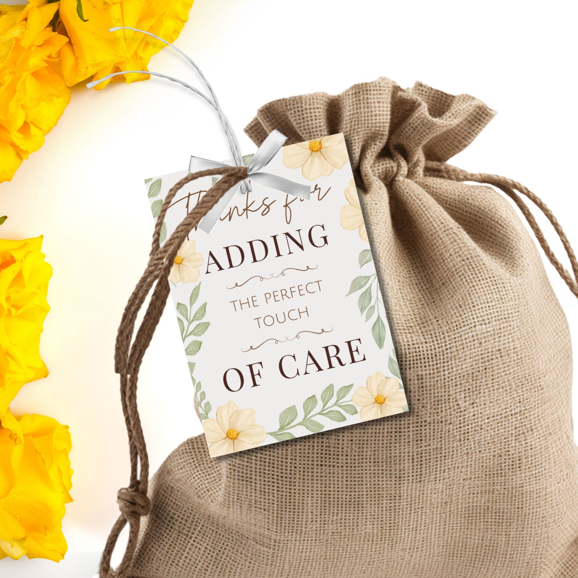 Burlap bag with a decorative tag reading 'Thanks for adding the perfect touch of care' against a yellow flower background.