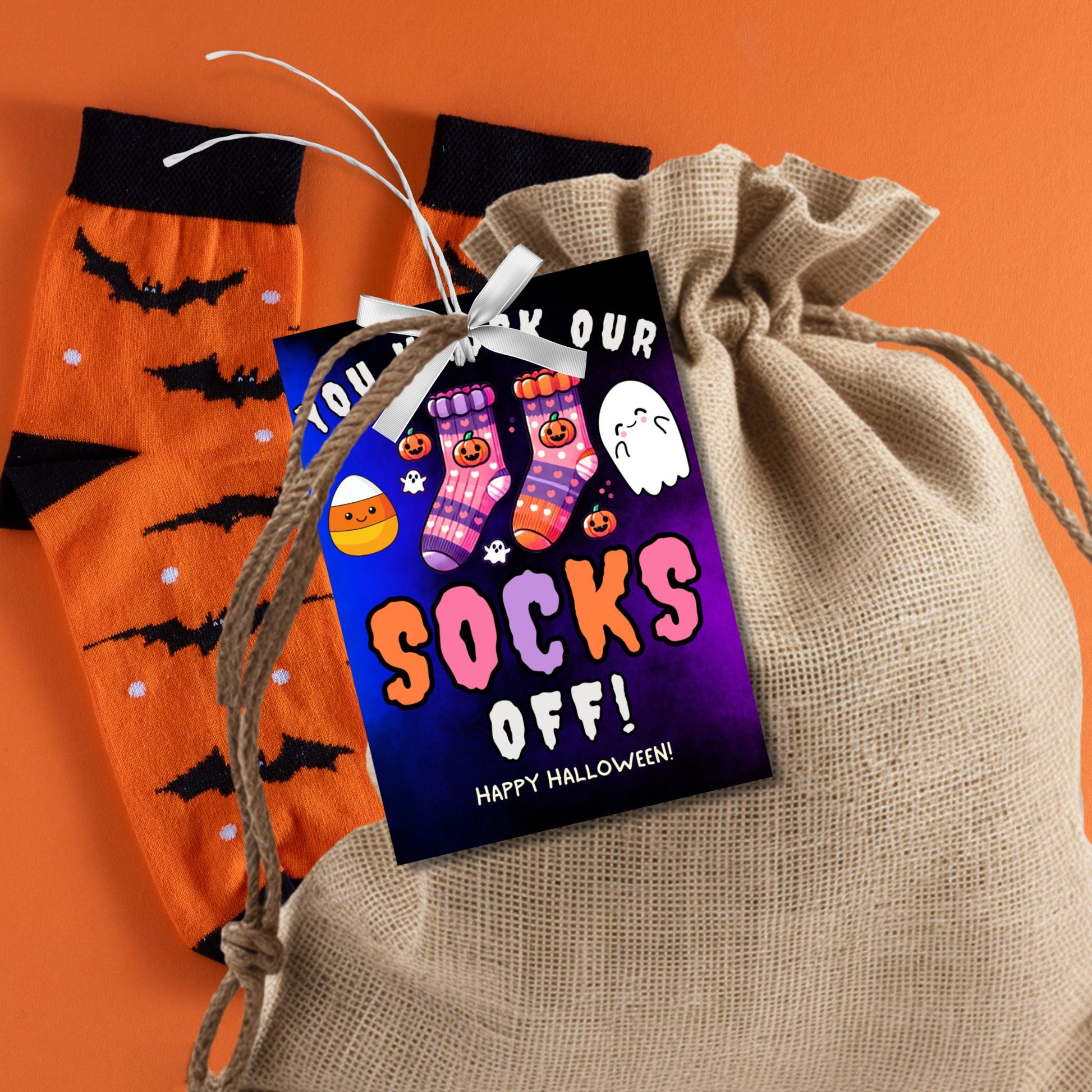 Halloween-themed printable gift tags with the message "You Knock Our Socks Off!" featuring colorful Halloween socks, ghosts, and candy corn. Tags are 2.5 x 3.5 inches, laid out 8 per sheet on a standard 8.5 x 11-inch page. Includes a printable PDF and a PDF with a link to an editable Canva template.