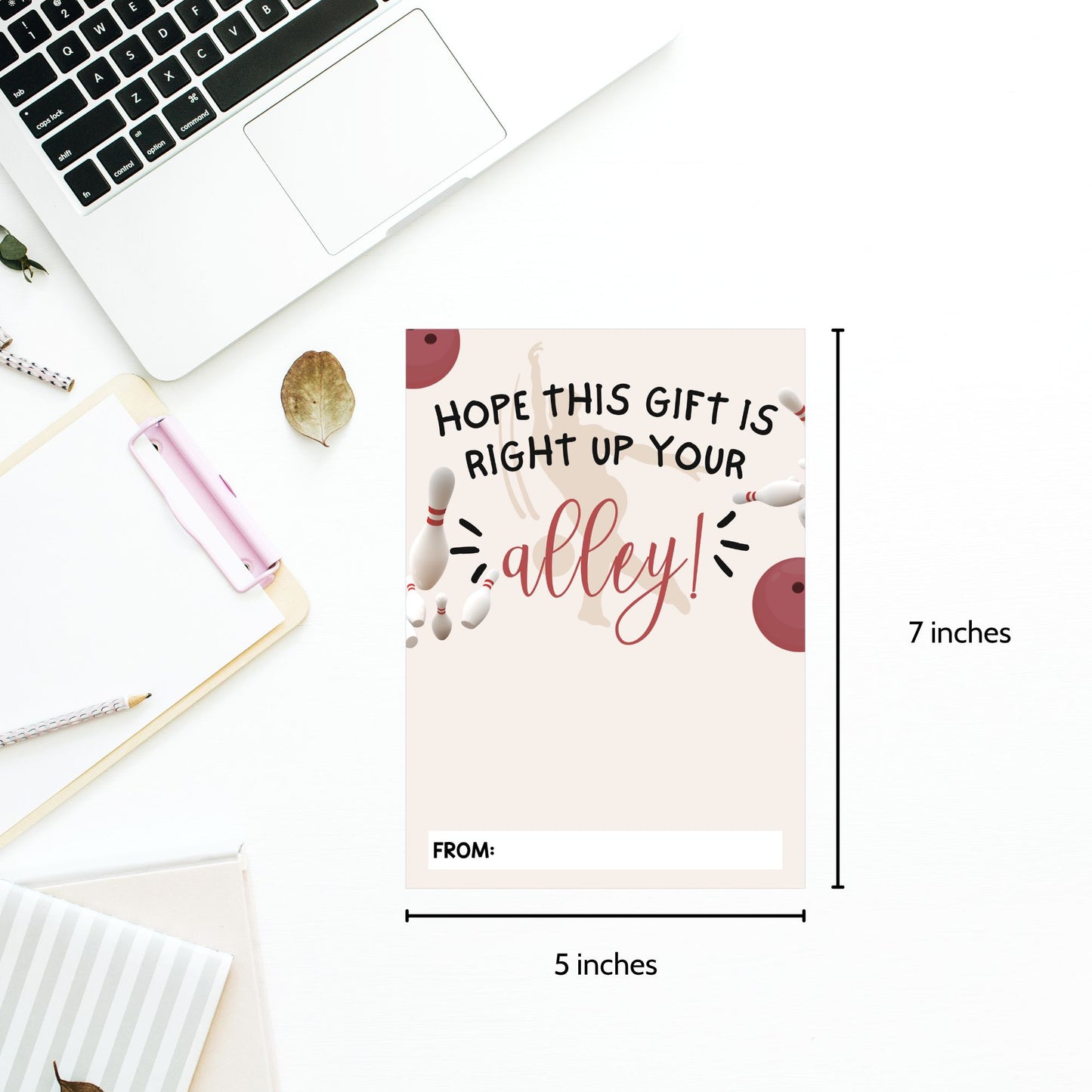 A flat-lay product photo of a personalized bowling-themed gift tag on a white desk background. The tag features a light pink background with illustrations of bowling pins, bowling balls, and the text 'HOPE THIS GIFT IS RIGHT UP YOUR alley!' with a blank 'FROM:' line.