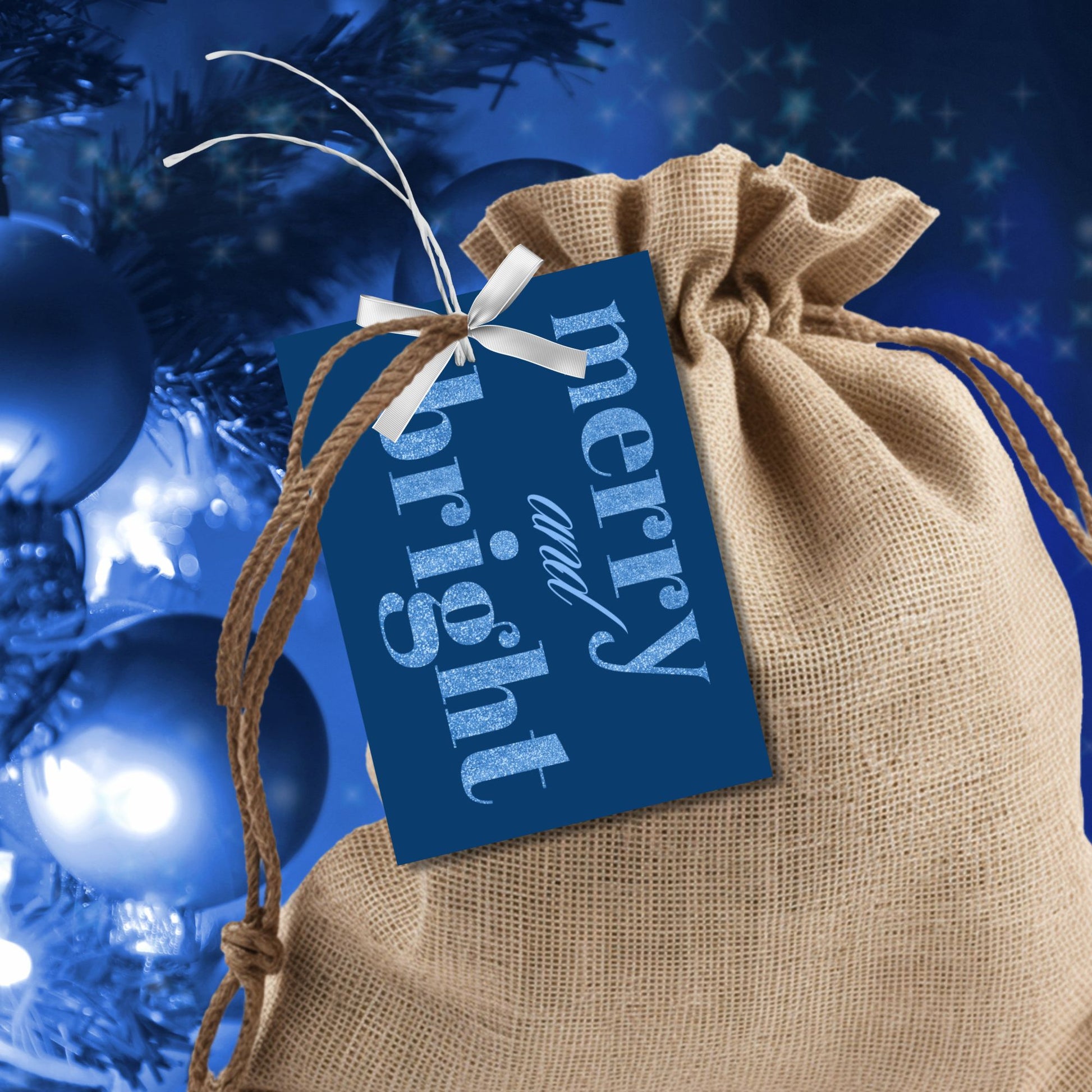 A set of ready-to-print Christmas gift tags featuring glittering icy blue text on a deep navy-blue background with festive messages like "Merry and Bright" and "Season's Greetings." Each tag is 2.5 x 3.5 inches, perfect for adding a frosty, elegant touch to holiday gifting.