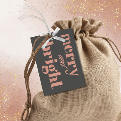 A set of ready-to-print Christmas gift tags featuring a luxurious rose gold glitter text on a bold charcoal background with festive messages like "Merry and Bright" and "Season's Greetings." Each tag measures 2.5 x 3.5 inches.