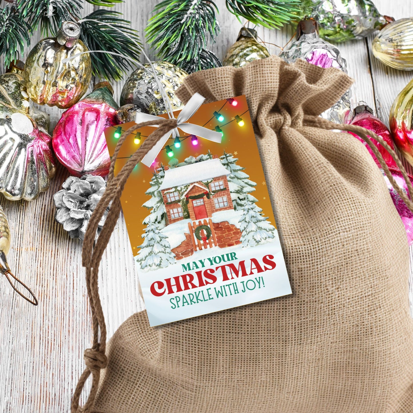 Christmas gift tags featuring a cozy snow-covered house decorated with festive lights, paired with the message "May Your Christmas Sparkle with Joy!" These printable and editable tags add a warm and festive touch to holiday gifts.