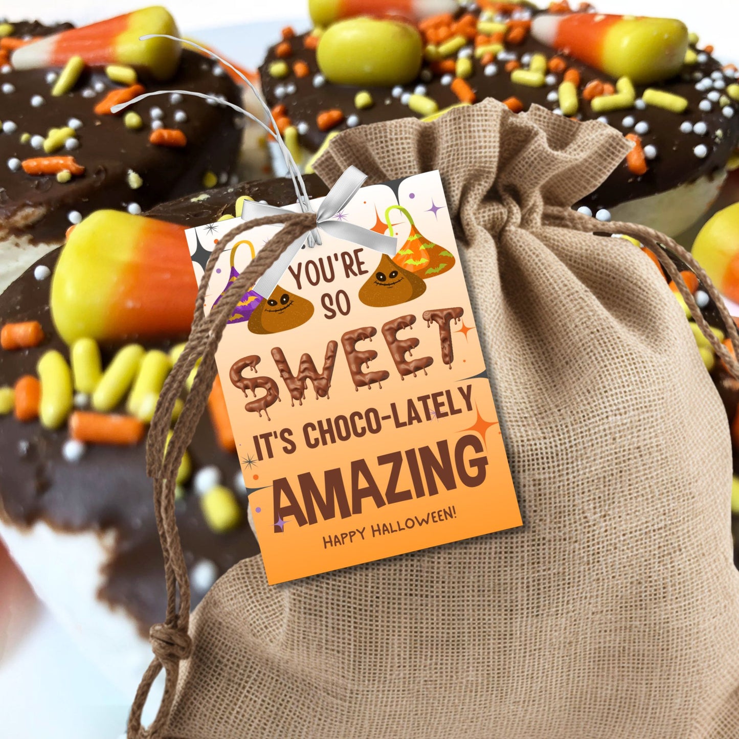 Halloween-themed printable gift tags with the message "You're So Sweet It's Choco-lately Amazing" featuring playful chocolate designs. Tags are 2.5 x 3.5 inches, laid out 8 per sheet on a standard 8.5 x 11-inch page. Includes a printable PDF and a PDF with a link to an editable Canva template.