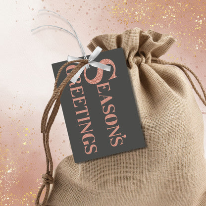 A set of ready-to-print Christmas gift tags featuring a luxurious rose gold glitter text on a bold charcoal background with festive messages like "Merry and Bright" and "Season's Greetings." Each tag measures 2.5 x 3.5 inches.