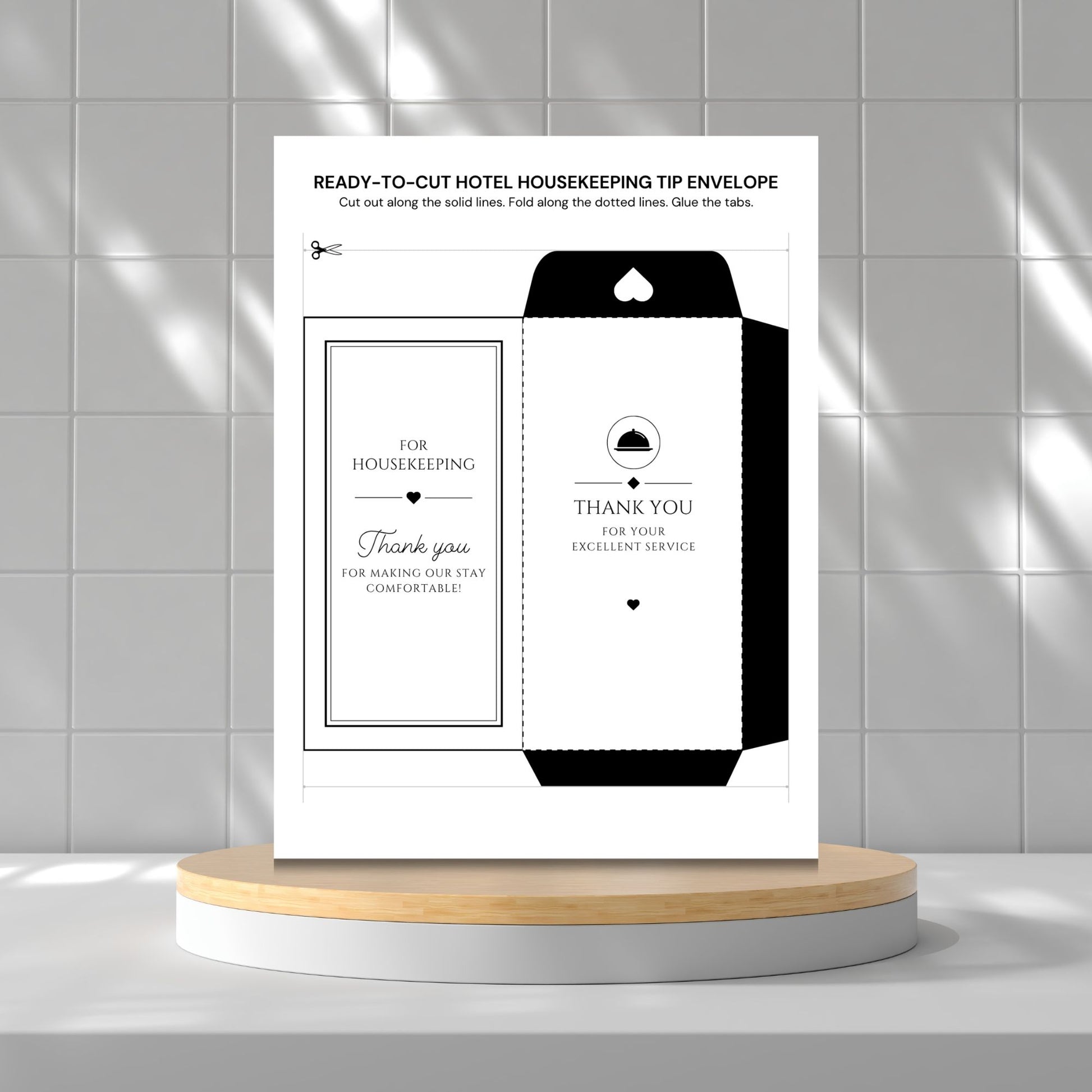 A printed housekeeping tip envelope template sheet displayed upright on a round wooden pedestal against a light gray tiled wall. The sheet shows a black-and-white envelope design with text including 'READY-TO-CUT HOTEL HOUSEKEEPING TIP ENVELOPE' and 'THANK YOU FOR YOUR EXCELLENT SERVICE.