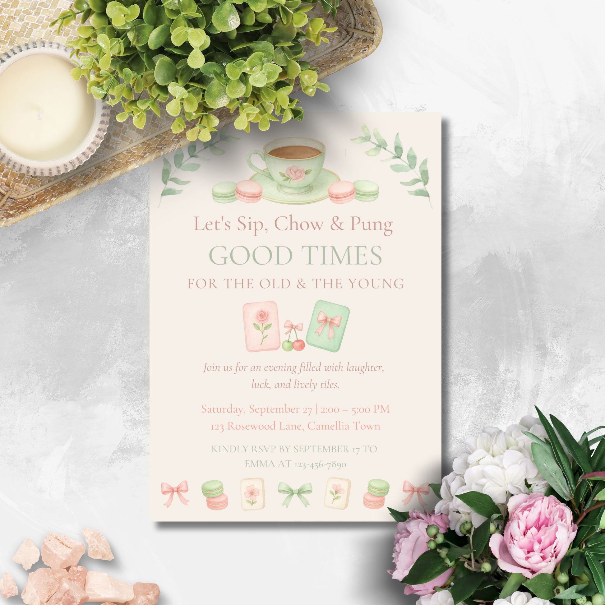 Invitation card with tea cup design on a white surface with flowers and a plant.