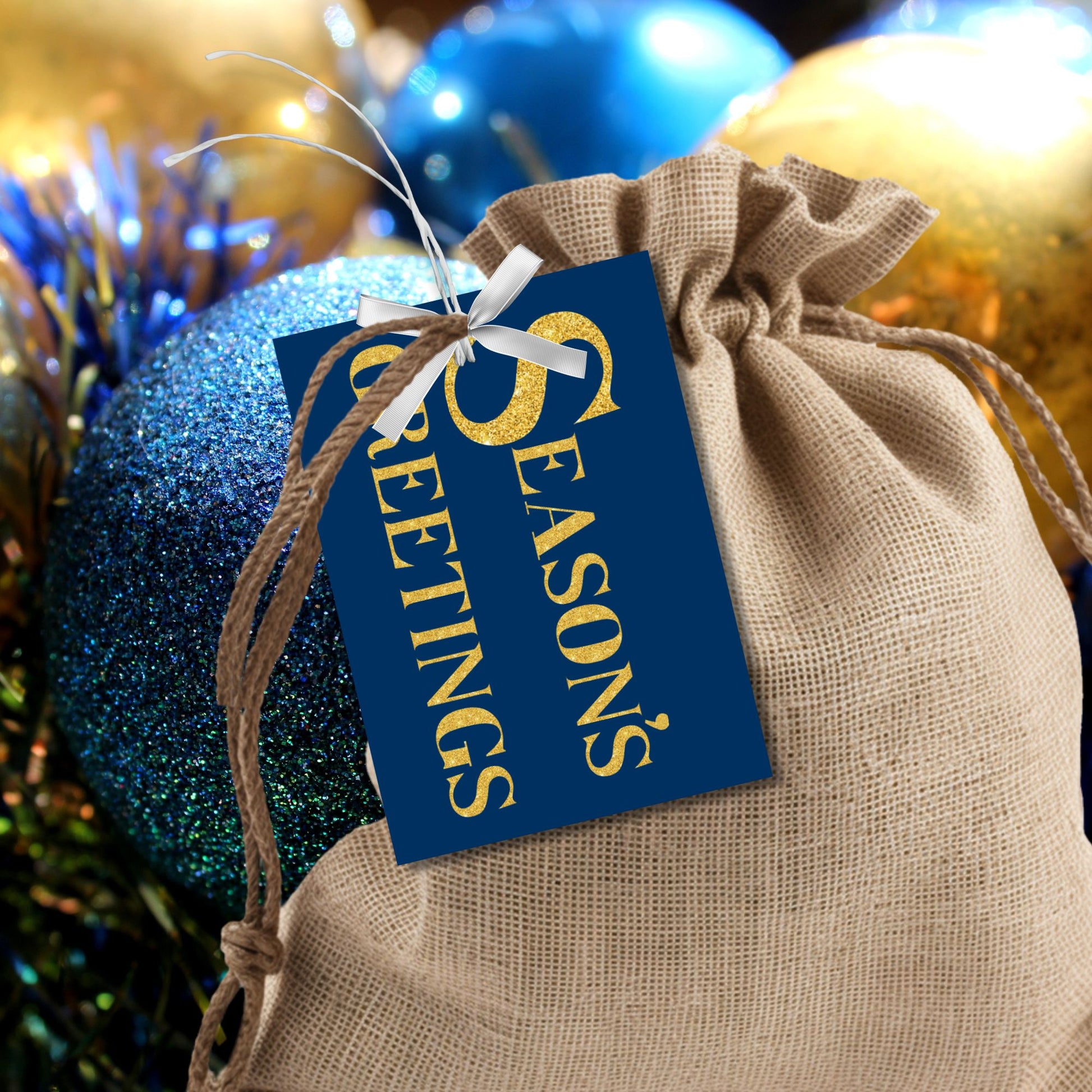 A set of ready-to-print Christmas gift tags featuring shimmering gold glitter text on a royal blue background with festive messages like "Merry and Bright" and "Season's Greetings." Each tag is sized at 2.5 x 3.5 inches, ideal for adding a luxurious touch to holiday gifting.