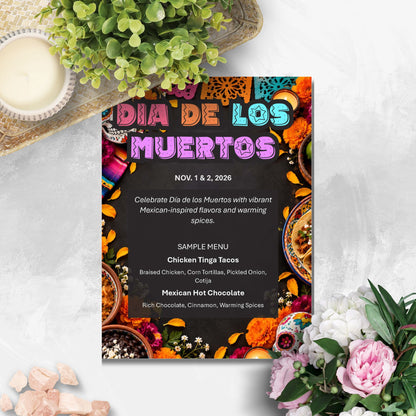 A Dia de los Muertos sample menu card styled in a flat-lay arrangement with flowers, a candle, and greenery on a light gray surface.