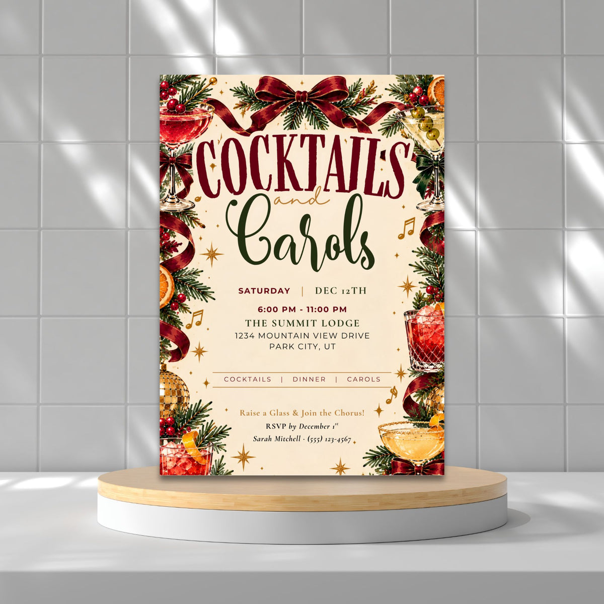 A festive Christmas-themed cocktail and carols event invitation card displayed on a white and light wood pedestal against a gray tiled wall with soft shadows.