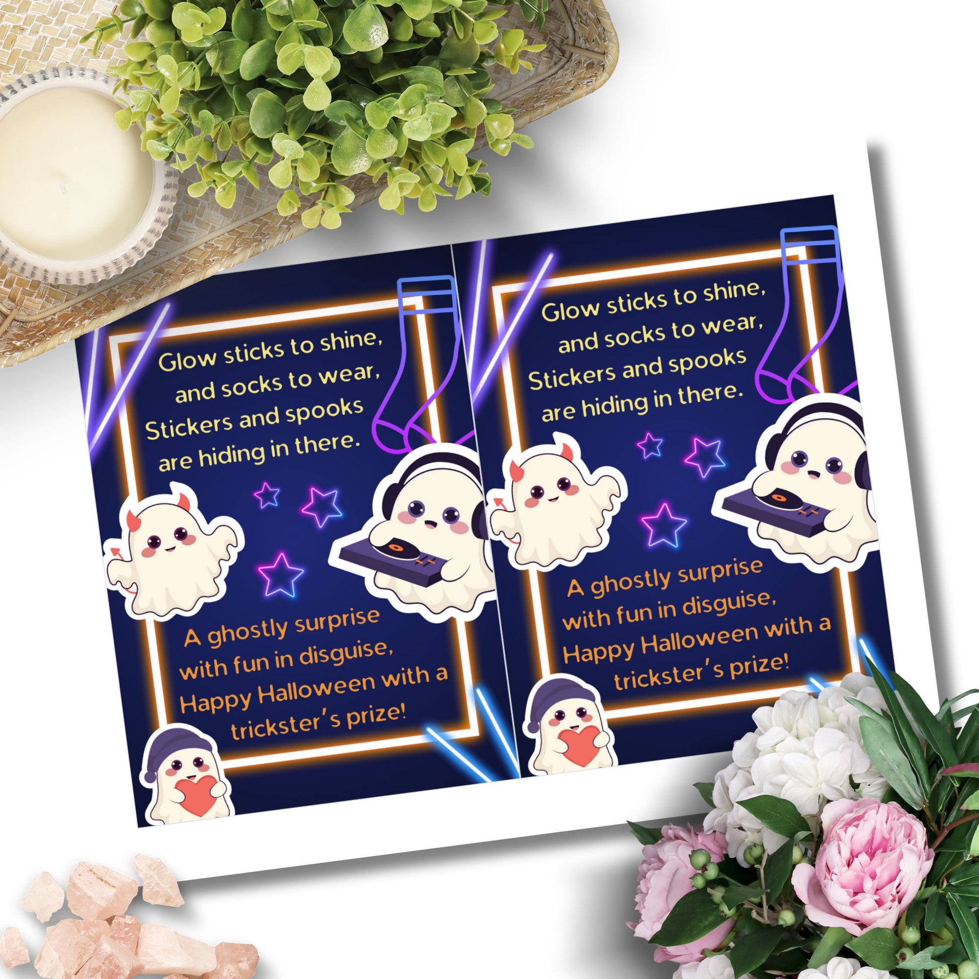 Halloween-themed cards with ghost illustrations and text on a white surface with flowers and a candle.