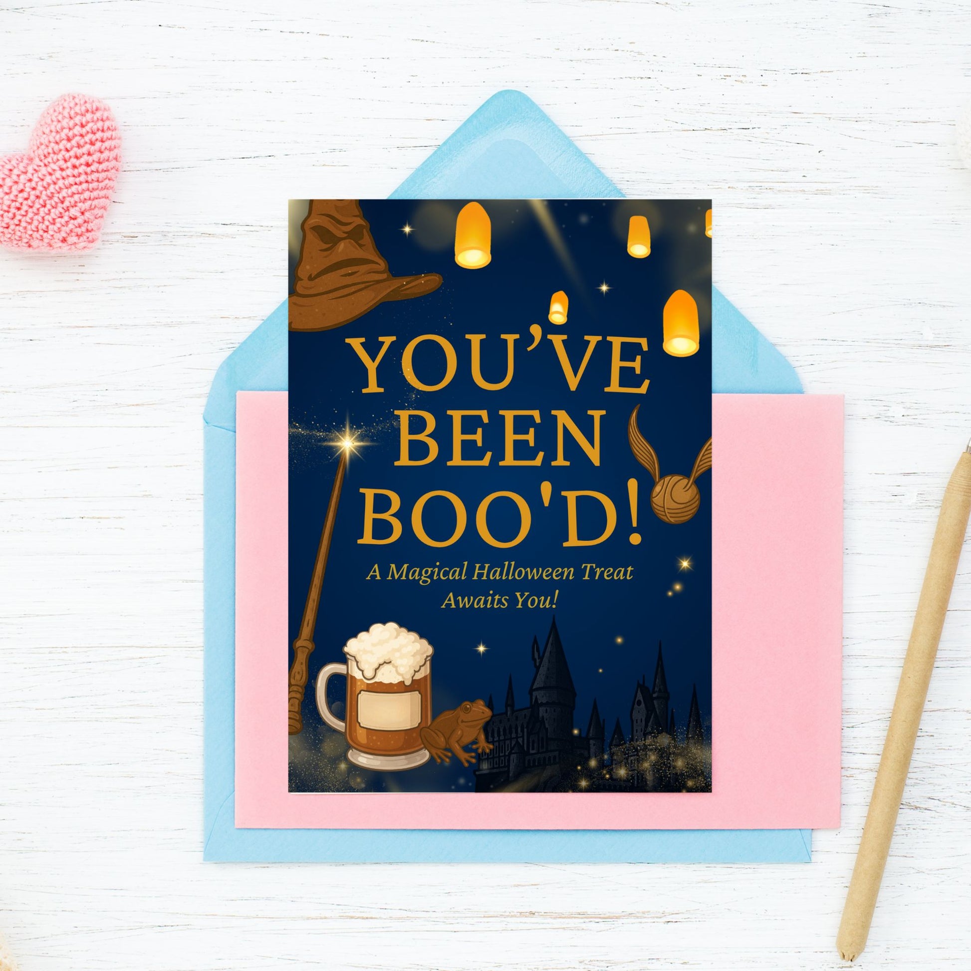 Halloween-themed 'You've Been Boo'd!' card with a blue envelope on a white wooden surface.